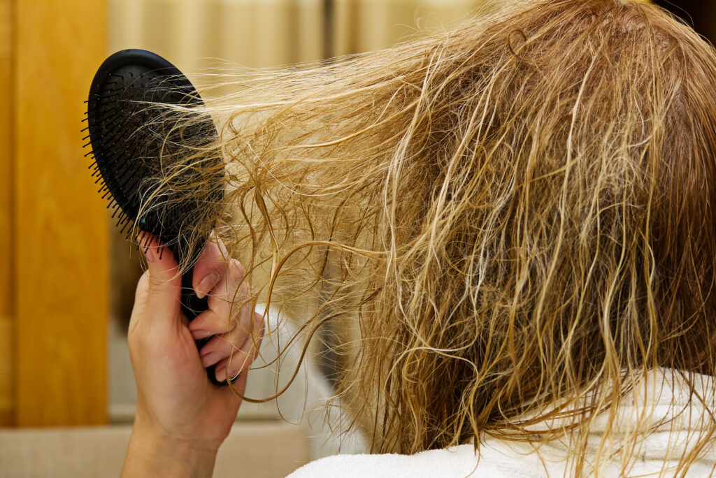 person brushing damp, dry hair 